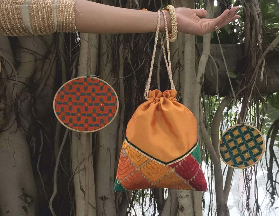 Embroidered bags hanging among the aerial roots of a banyan tree
