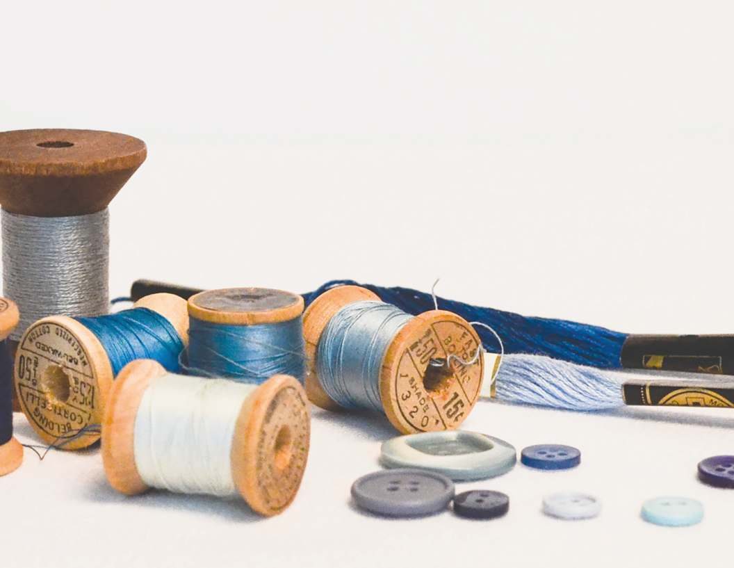 Wooden spools of thread and buttons on a pale surface